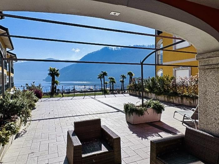 Eine ca. 100 m² große, teils überdachte Terrasse mit herrlichem Panoramablick auf den See, die umliegenden Berge und den gepflegten Palmengarten