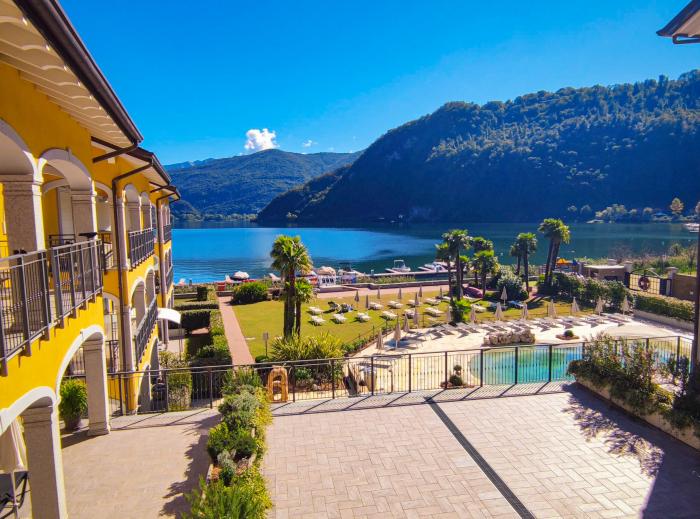 Eine ca. 100 m² große, teils überdachte Terrasse mit herrlichem Panoramablick auf den See, die umliegenden Berge und den gepflegten Palmengarten