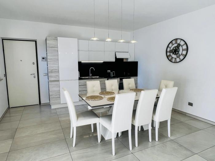 Moderne, helle Einbauküche mit Backofen, Geschirrspüler und großem Esstisch – ideal für geselliges Kochen und Genießen