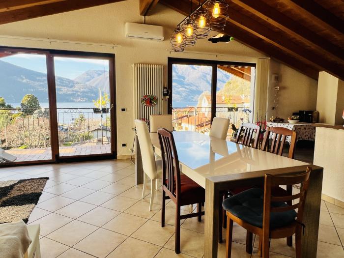 Weitläufiges Wohnzimmer mit viel Tageslicht, Balkonzugang und traumhaftem Panorama auf den See und die umliegende Berglandschaft