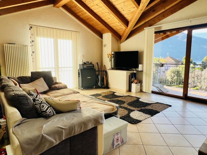 Weitläufiges Wohnzimmer mit viel Tageslicht, Balkonzugang und traumhaftem Panorama auf den See und die umliegende Berglandschaft