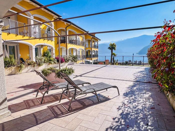 Eine ca. 100 m² große, teils überdachte Terrasse mit herrlichem Panoramablick auf den See, die umliegenden Berge und den gepflegten Palmengarten