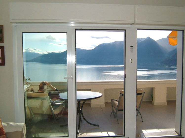 Wohn-/ Esszimmer mit großen Panoramaschiebetüren und gigantischer Sicht auf den See und die Berge